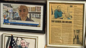 Framed TV and newspaper clippings about the shop on the wall, including a Chelsea News page